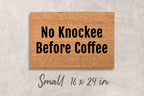 A rectangular brown doormat with the text "No Knockee Before Coffee" printed on it.